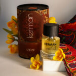 عطر کرمان هانی مون در کنار گل های زیبا و بسته بندی خاص